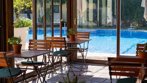 Ein Sitzbereich im Freien mit Tischen und Stühlen mit Blick auf einen Swimmingpool.