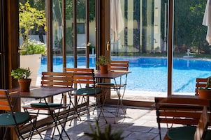Zona esterna con tavoli e sedie, affacciata su una piscina.