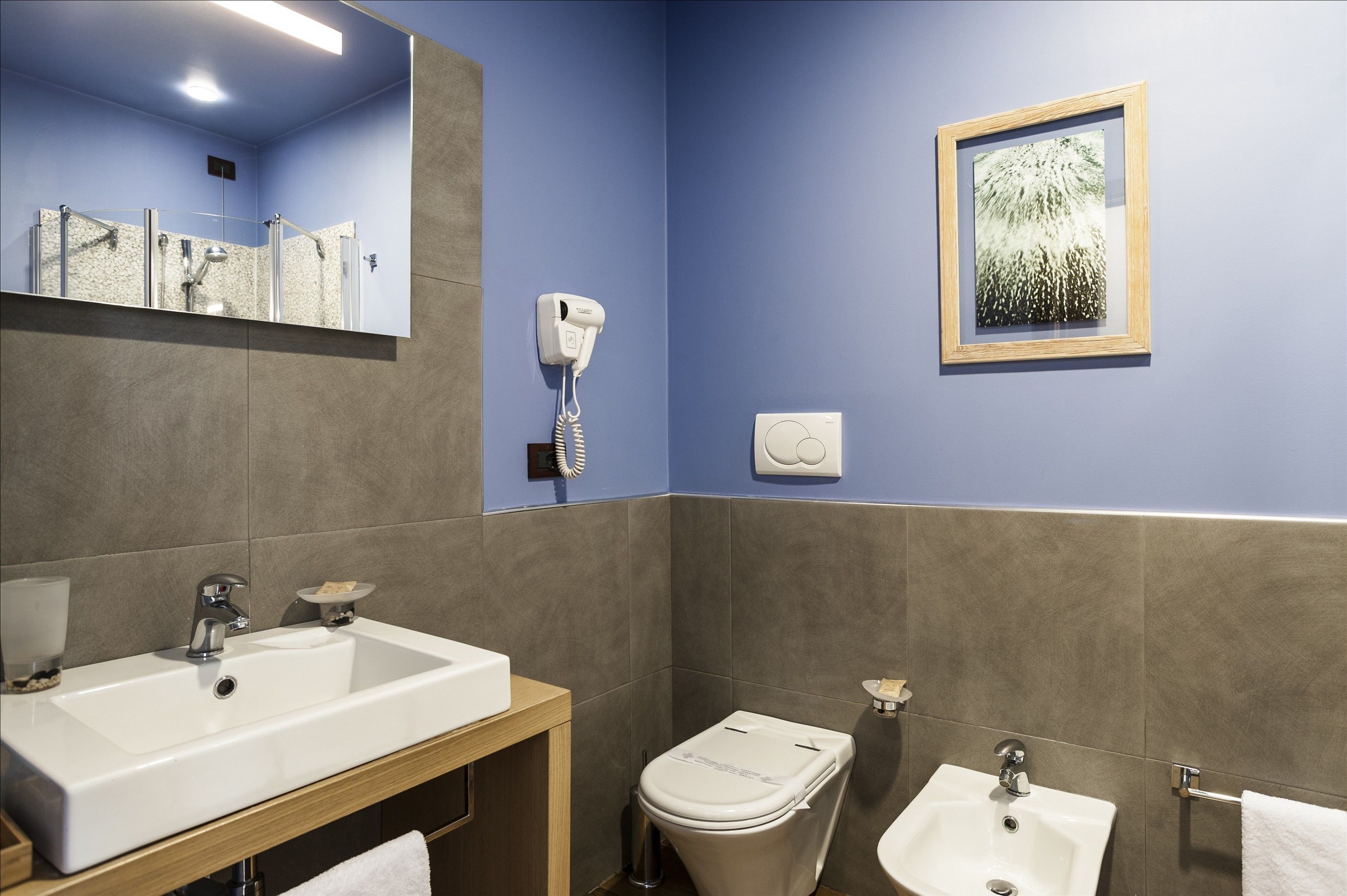 A bathroom with a sink, mirror, toilet, and bidet.