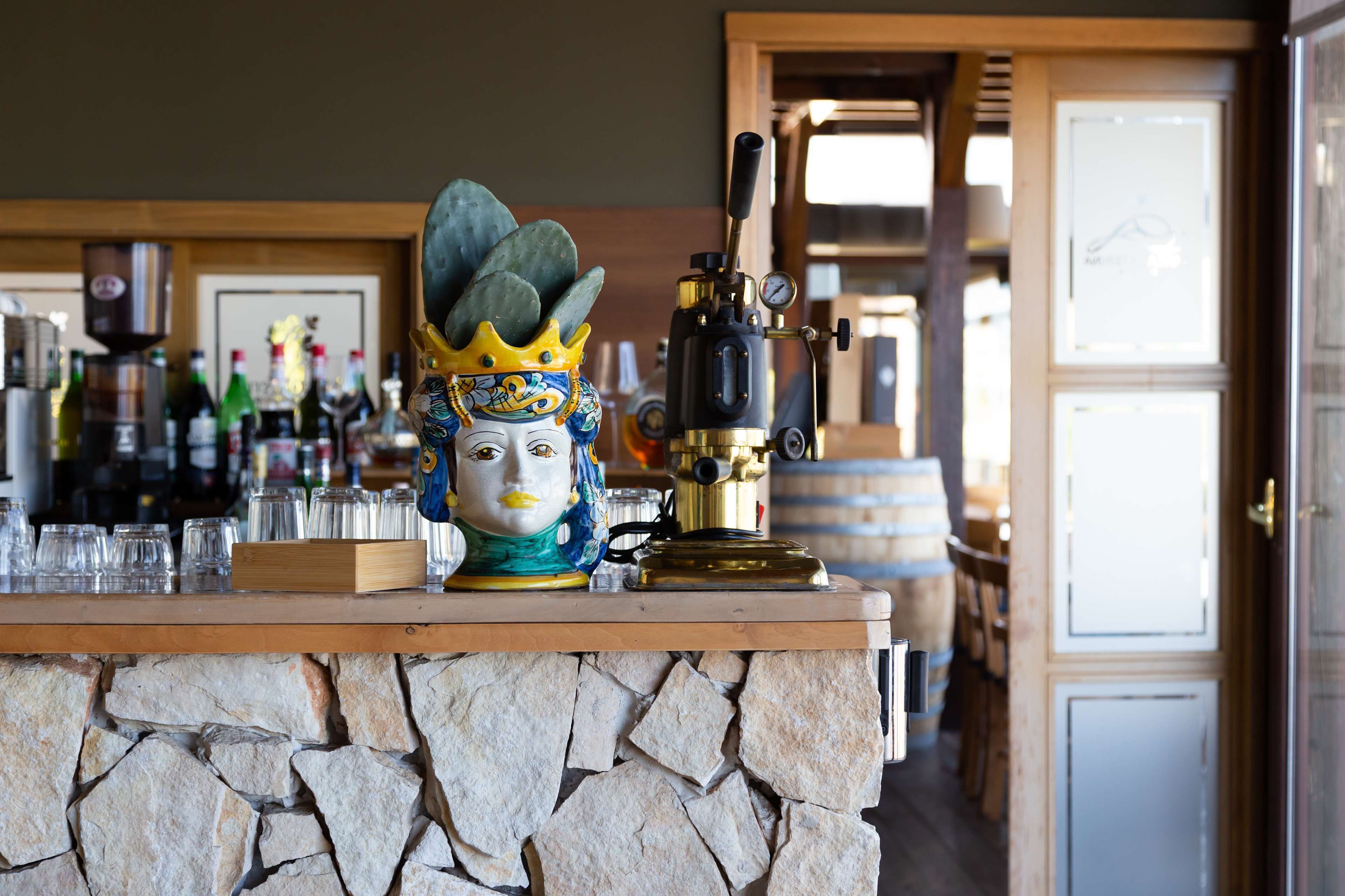 A bar area with a stone counter, a decorative mask, and a coffee machine.