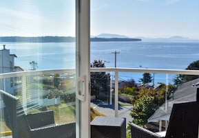 Varanda com mobiliário de vime com vista para a água e terra ao longe.