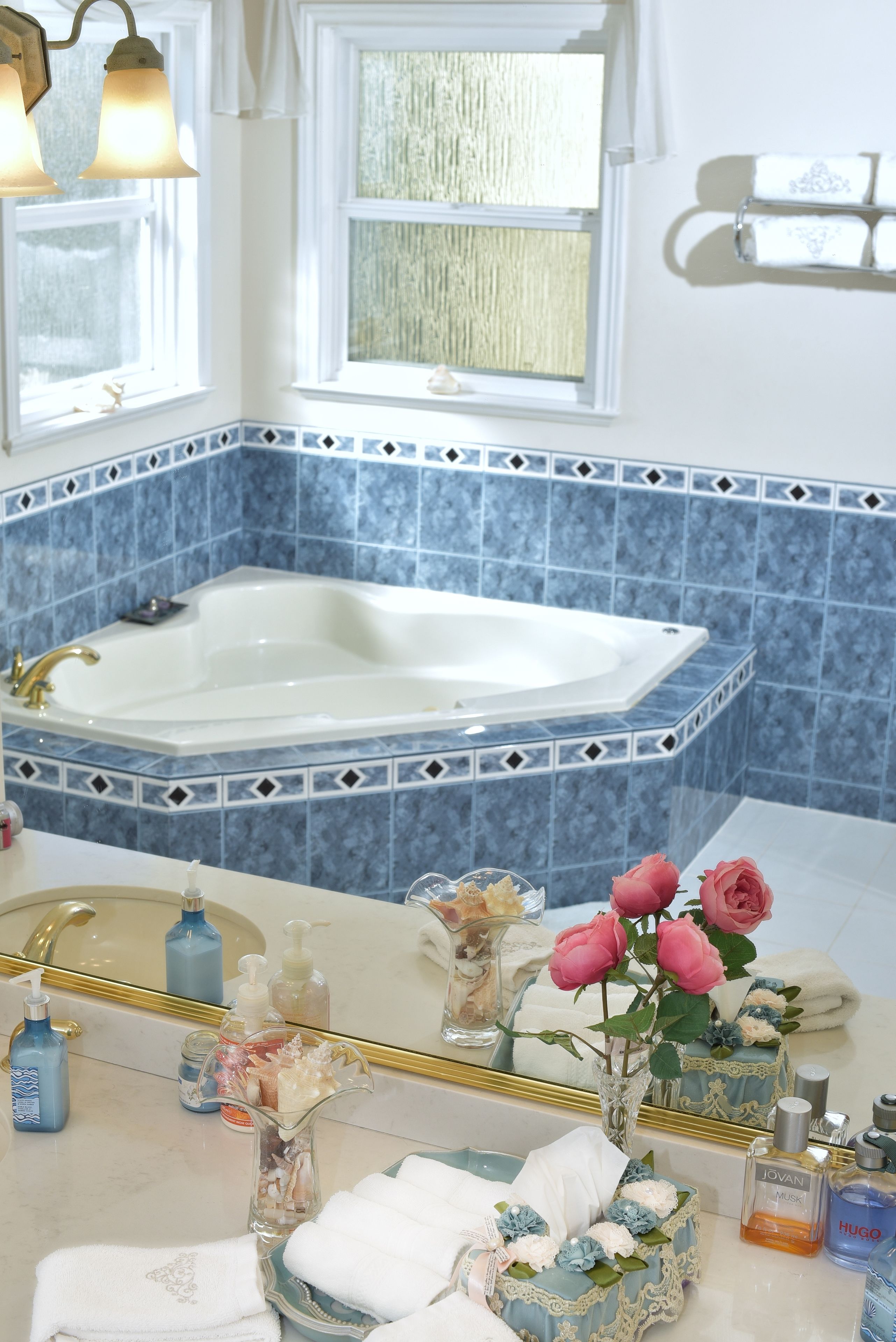 A bathroom with a large bathtub, a mirror, and a sink with toiletries.