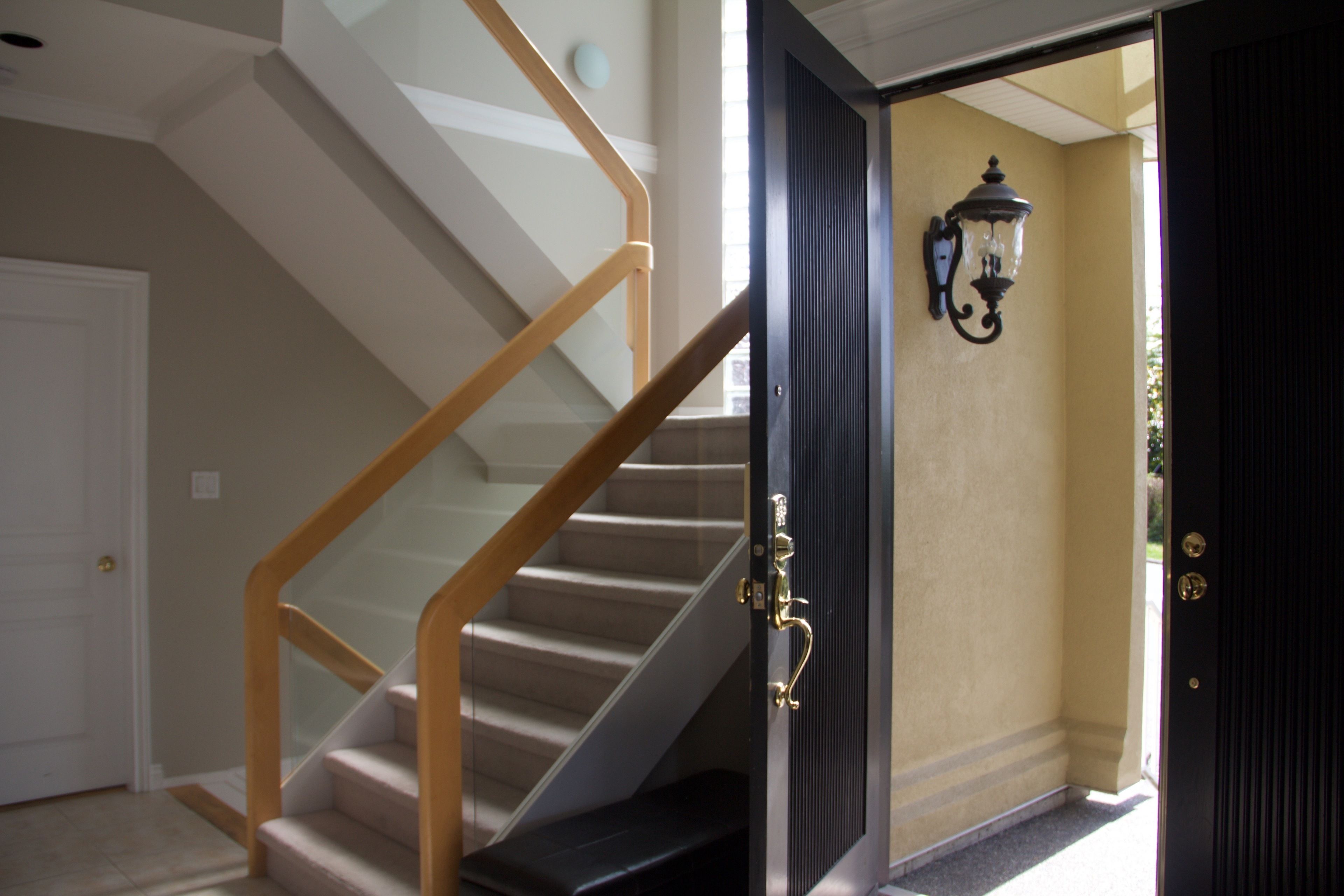 A staircase with wooden handrails and a black door with a glass panel.