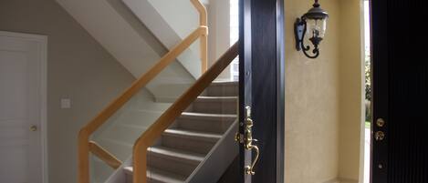 A staircase with wooden handrails and a black door with a glass panel.