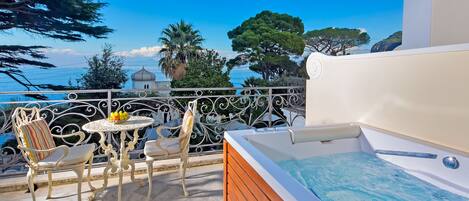 A balcony with a white bathtub, a table with fruit, and chairs.