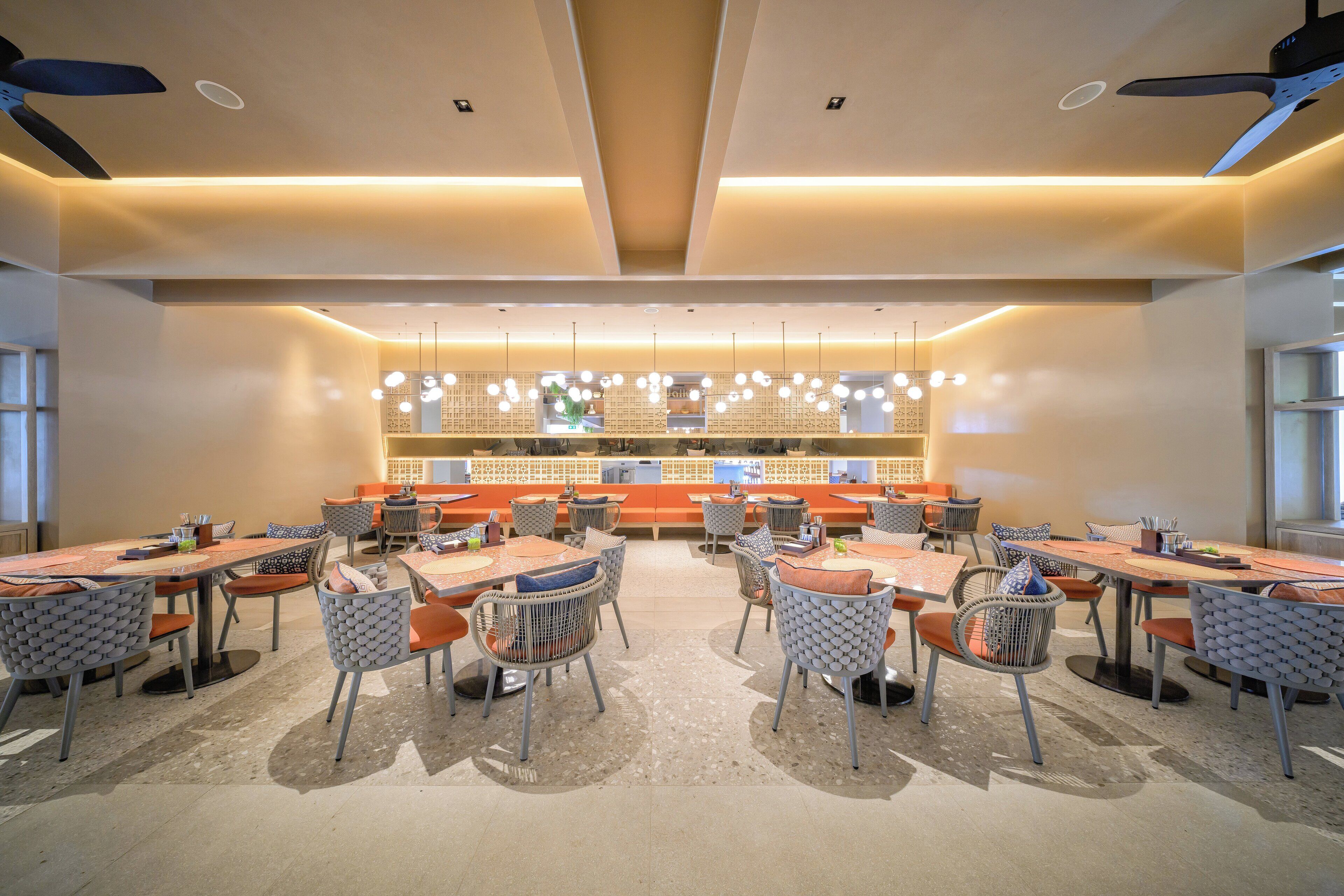 A spacious dining area with multiple tables and chairs, a central counter, and pendant lighting.