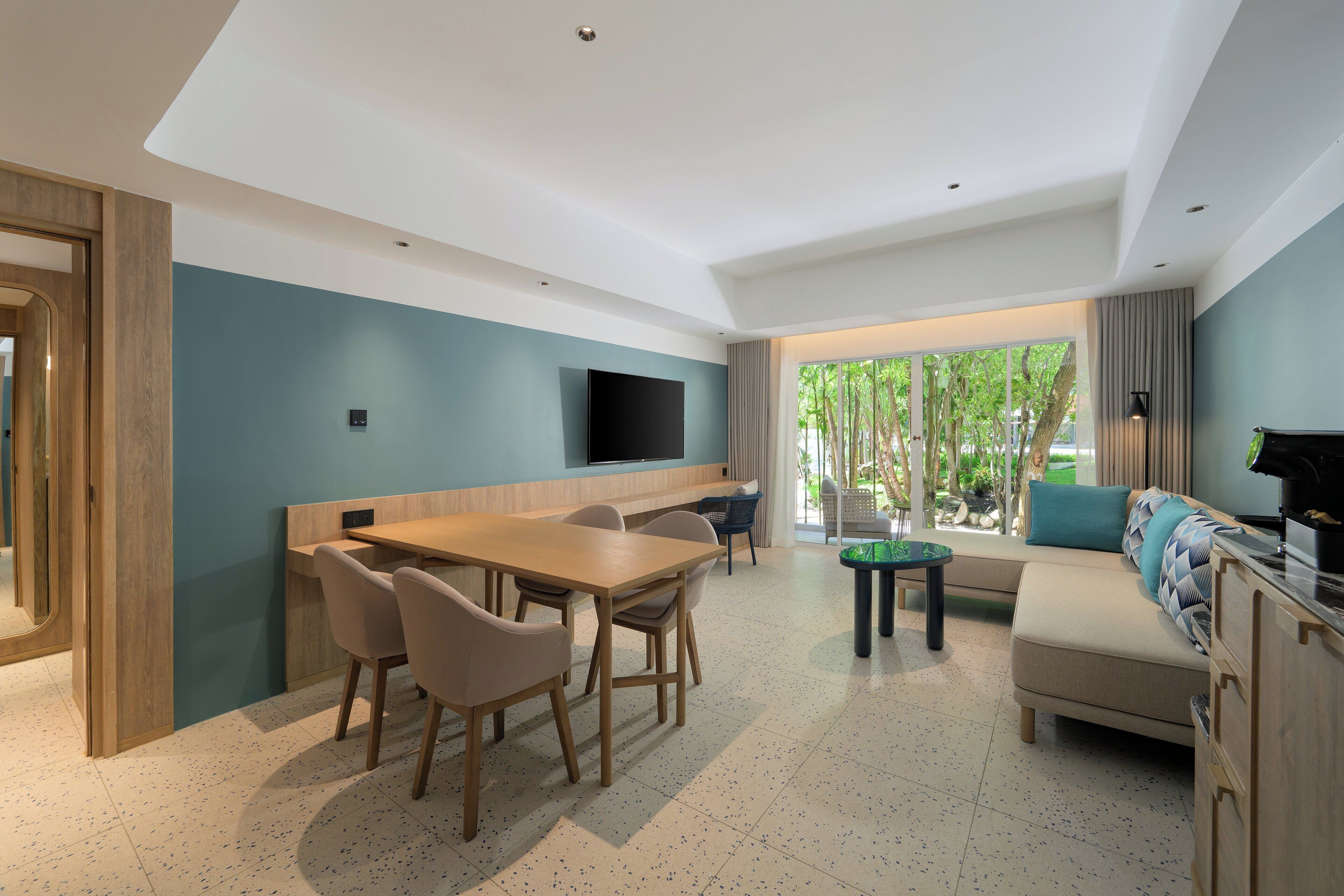Una sala de estar moderna con comedor, un sofá y un televisor montado en la pared.