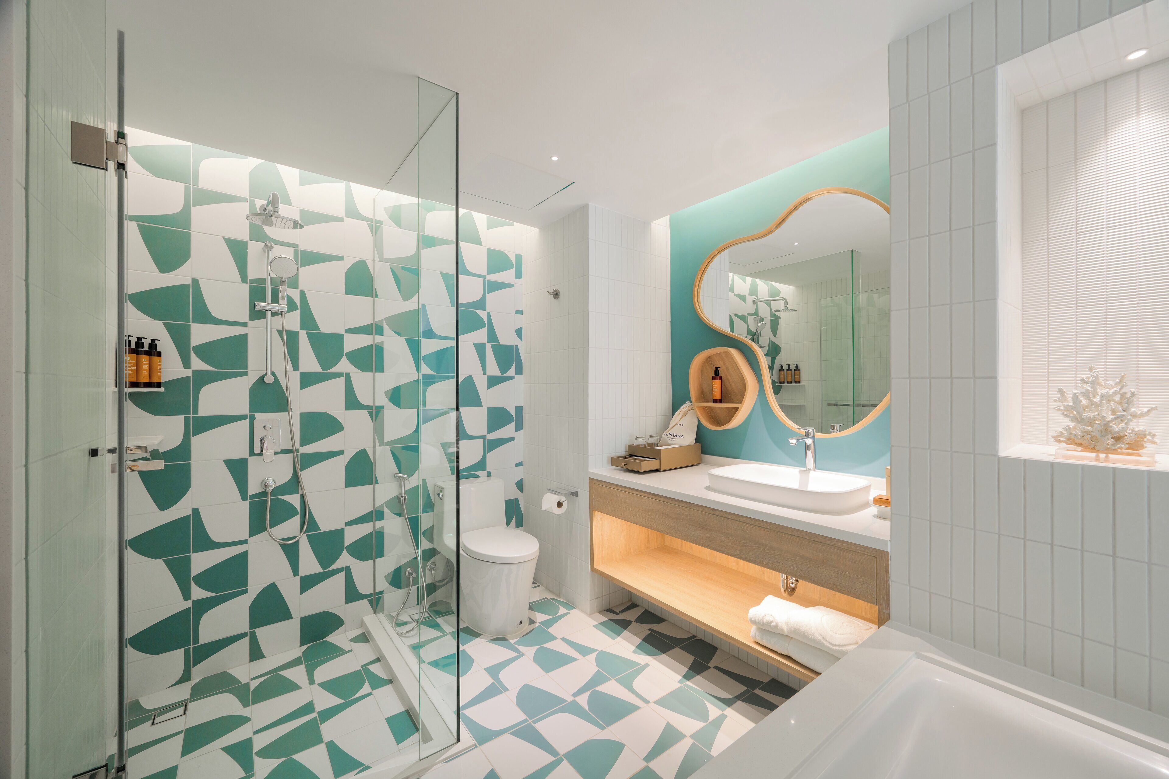 Un baño moderno con cabina de ducha de vidrio, inodoro blanco, lavabo con tocador de madera y bañera.
