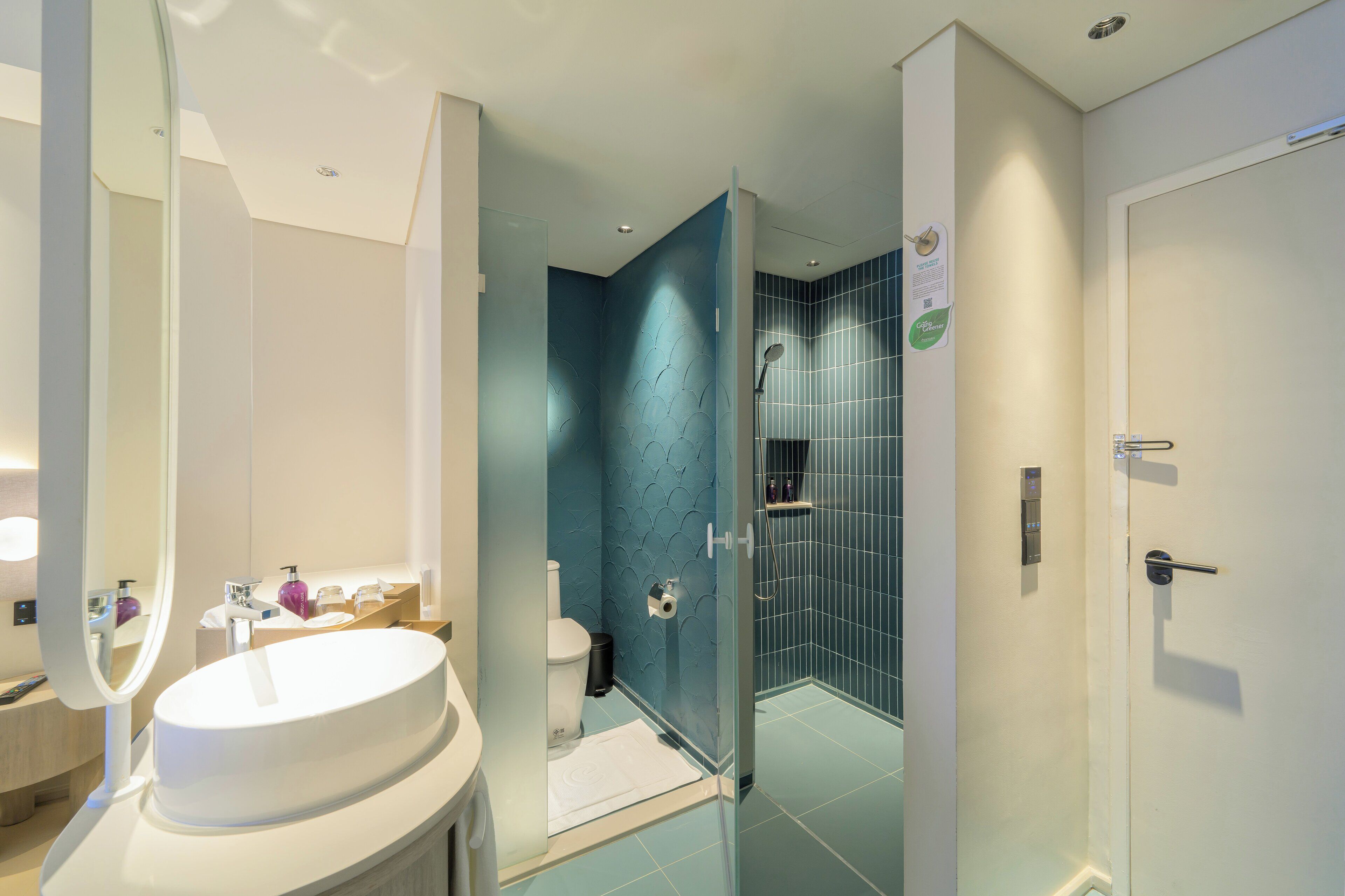 Un baño moderno con un lavamanos blanco, cabina de ducha de vidrio y un inodoro.