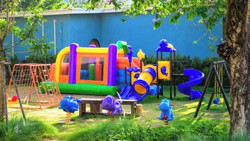 Ein Spielplatz mit Rutsche, Schaukeln und einer Kletterkonstruktion.