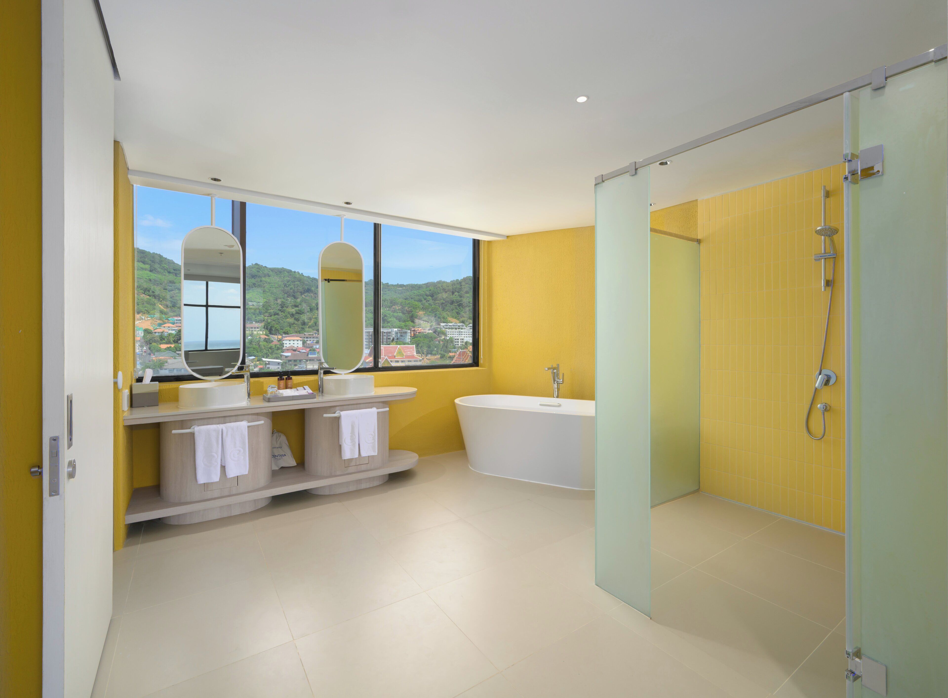 A modern bathroom with a bathtub, a shower, and a large window offering a city view.