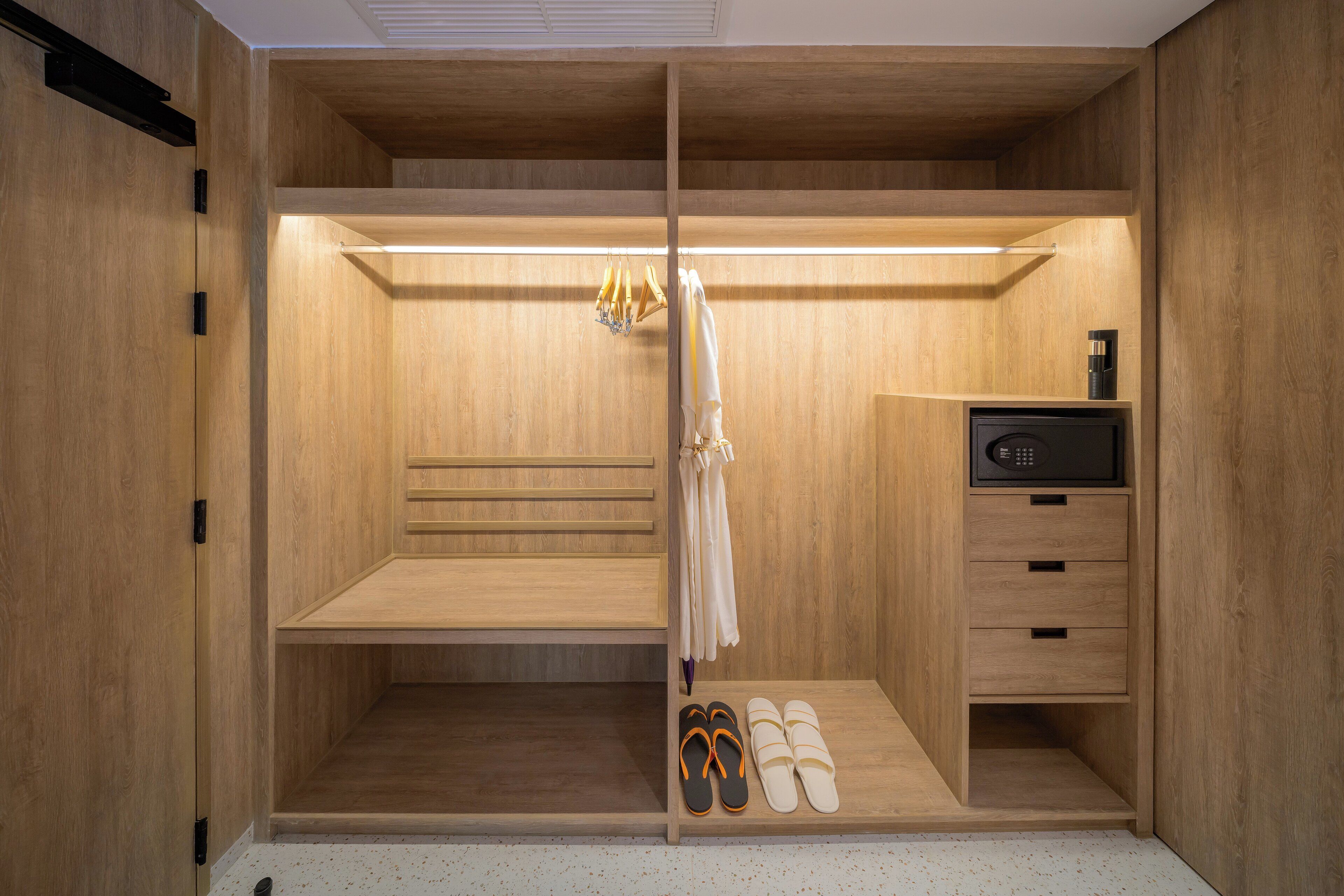 A walk-in closet with wooden shelving, a hanging rack, and a shoe rack.
