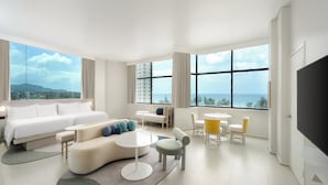 A modern hotel room with a large bed, a sofa, a coffee table, and a TV.