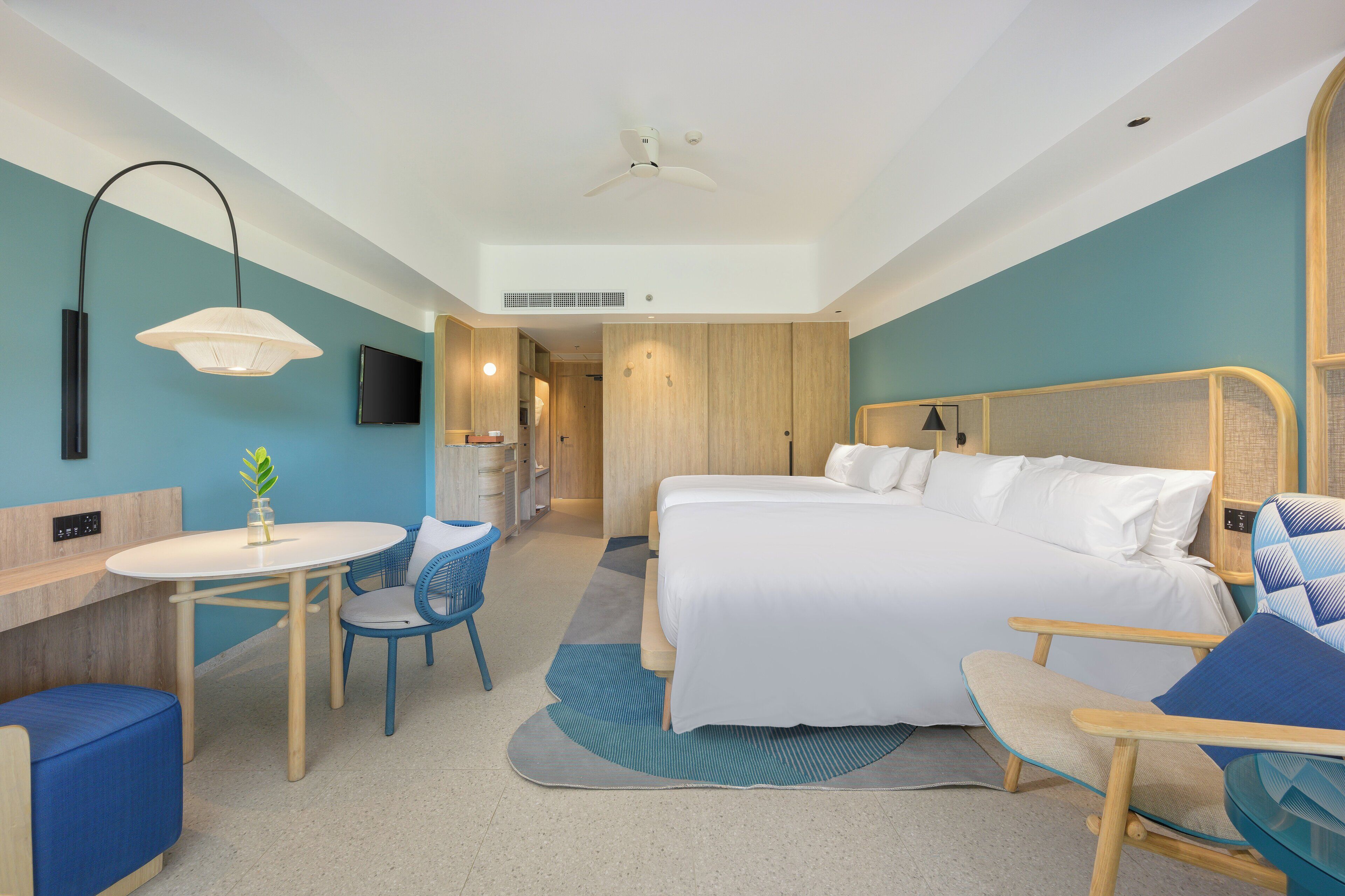Una moderna camera d'albergo con un letto, una scrivania, una sedia e una televisione.