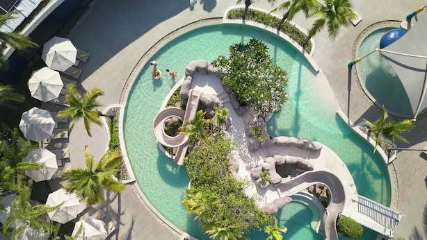 A circular pool with a central island, surrounded by palm trees and umbrellas. - Centara Karon Resort Phuket (Karon)