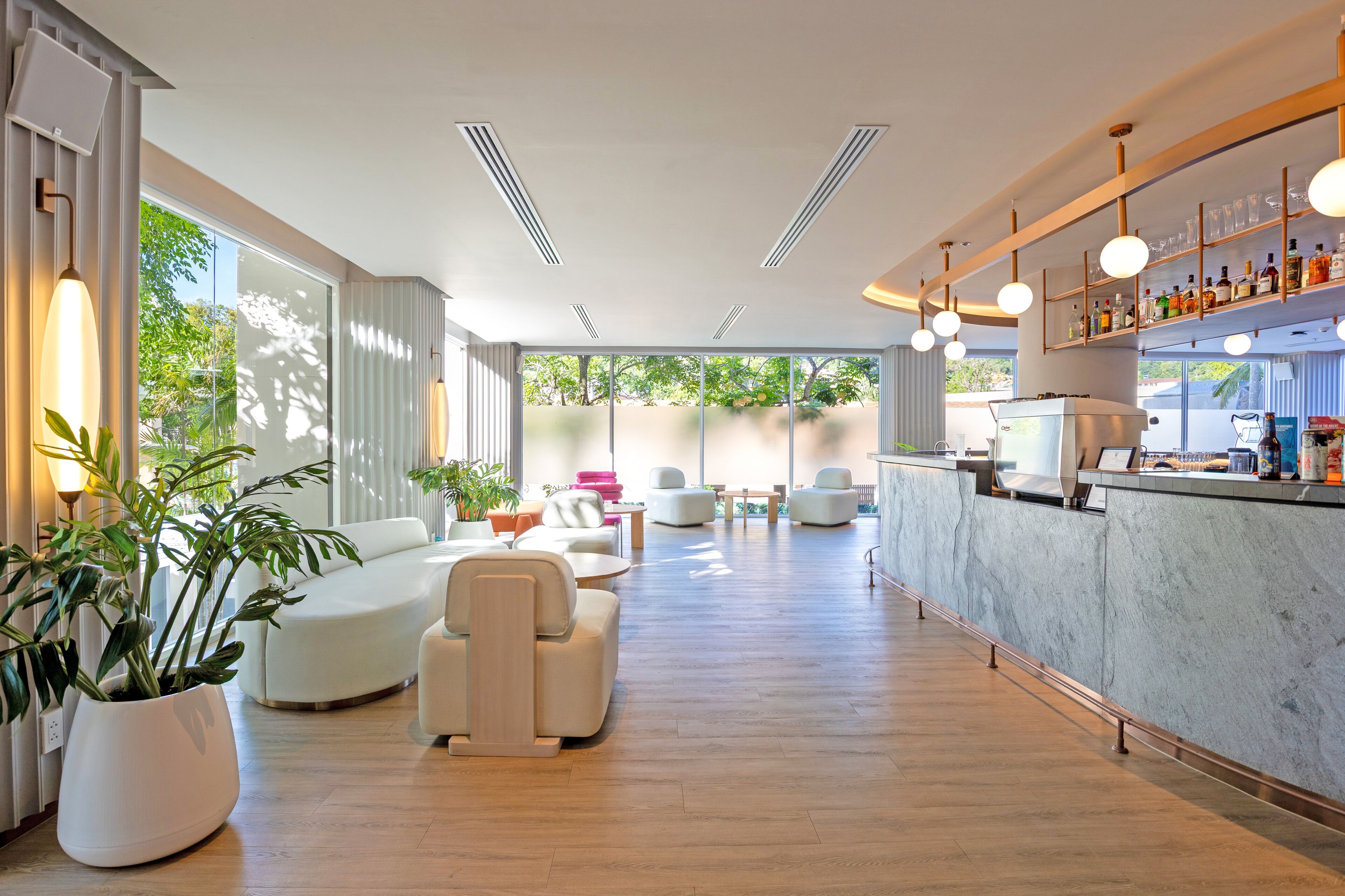 Un moderno vestíbulo de hotel con mostrador de recepción, zona de estar y grandes ventanales.