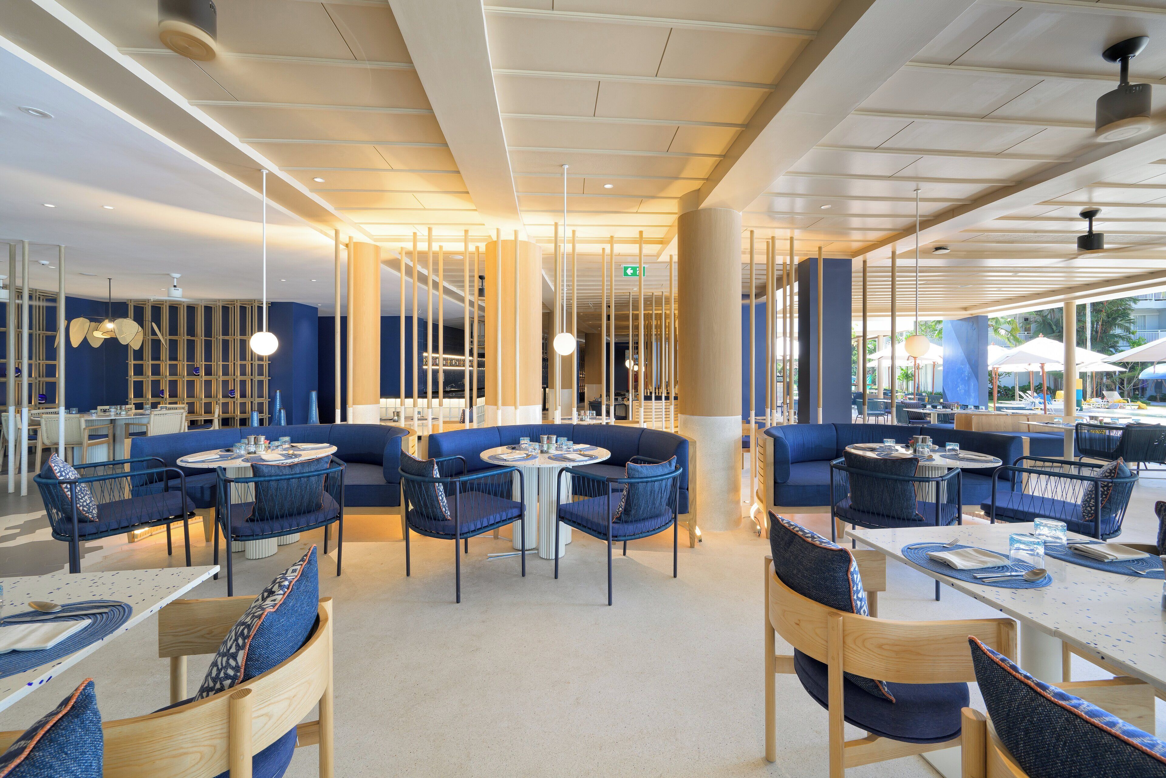 A modern restaurant with round tables and blue upholstered seating.