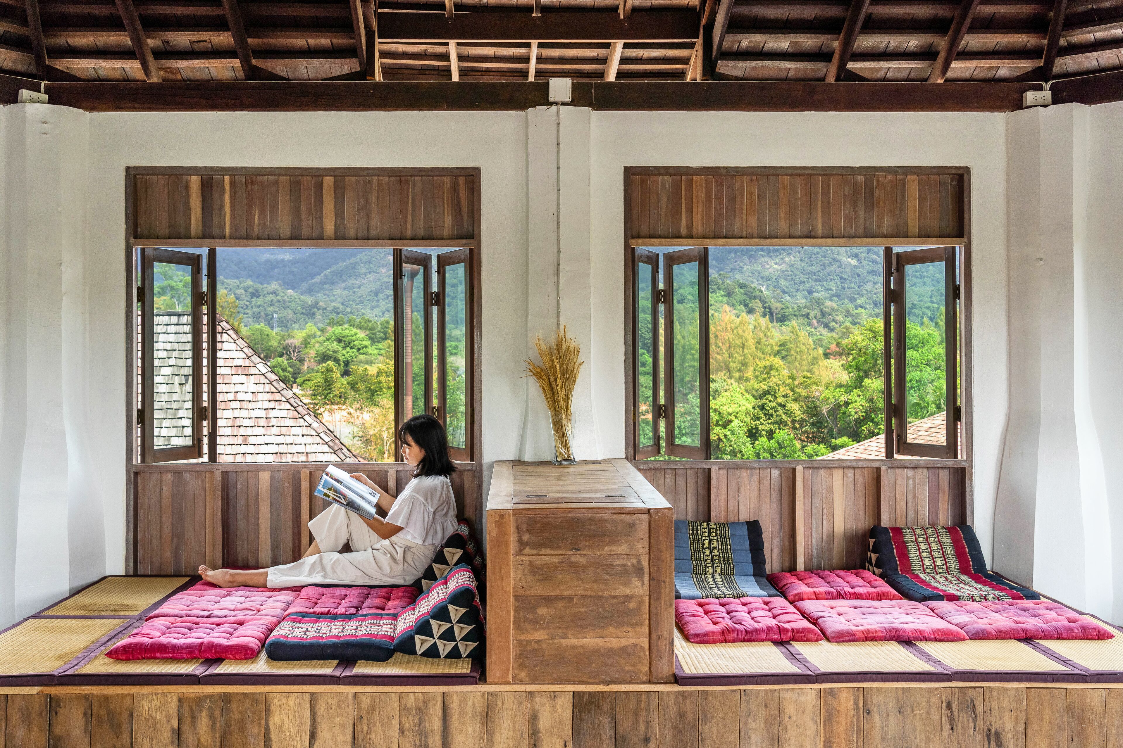 A room with a wooden ceiling and large windows offering a view of a mountainous landscape.
