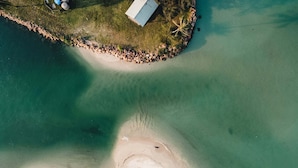 An aerial view of a beach with a small building and a rocky barrier. - Aana Resort & Spa (Ko Chang)