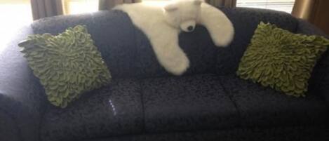 Un canapé bleu foncé sur lequel est posé un ours en peluche blanc.