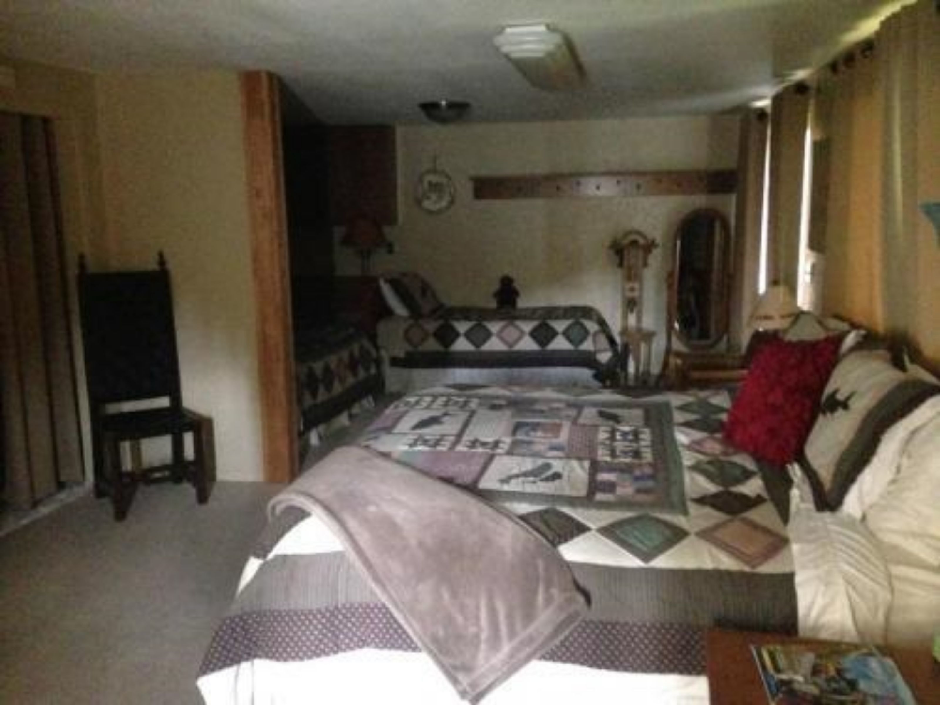Una camera da letto con un letto, una sedia, una cassettiera e uno specchio.