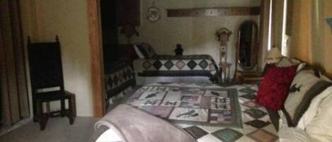 Una camera da letto con un letto, una sedia, una cassettiera e uno specchio.