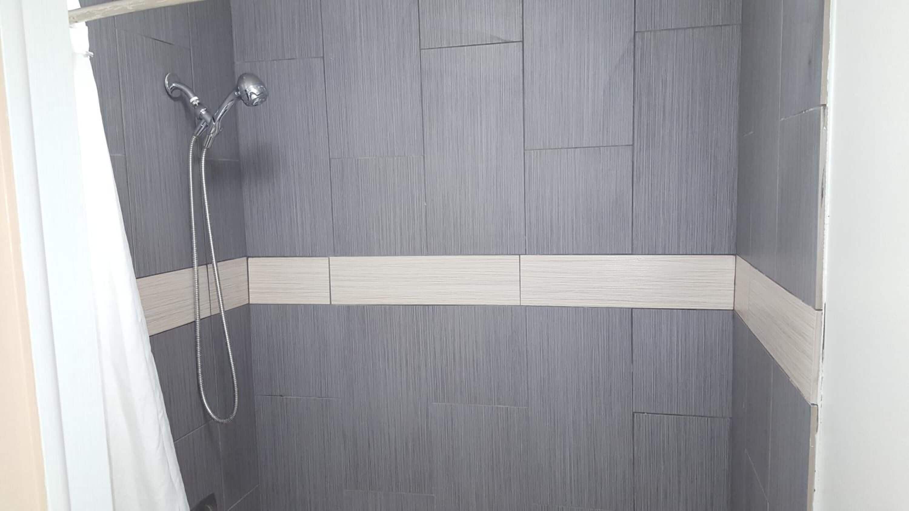 A shower with grey tiles and a white border.