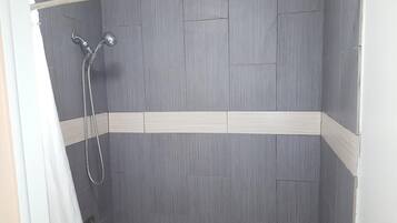 A shower with grey tiles and a white border.