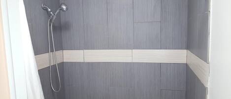 A shower with grey tiles and a white border.