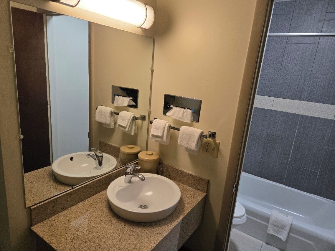 Un baño con dos lavamanos, un espejo y zona de ducha.