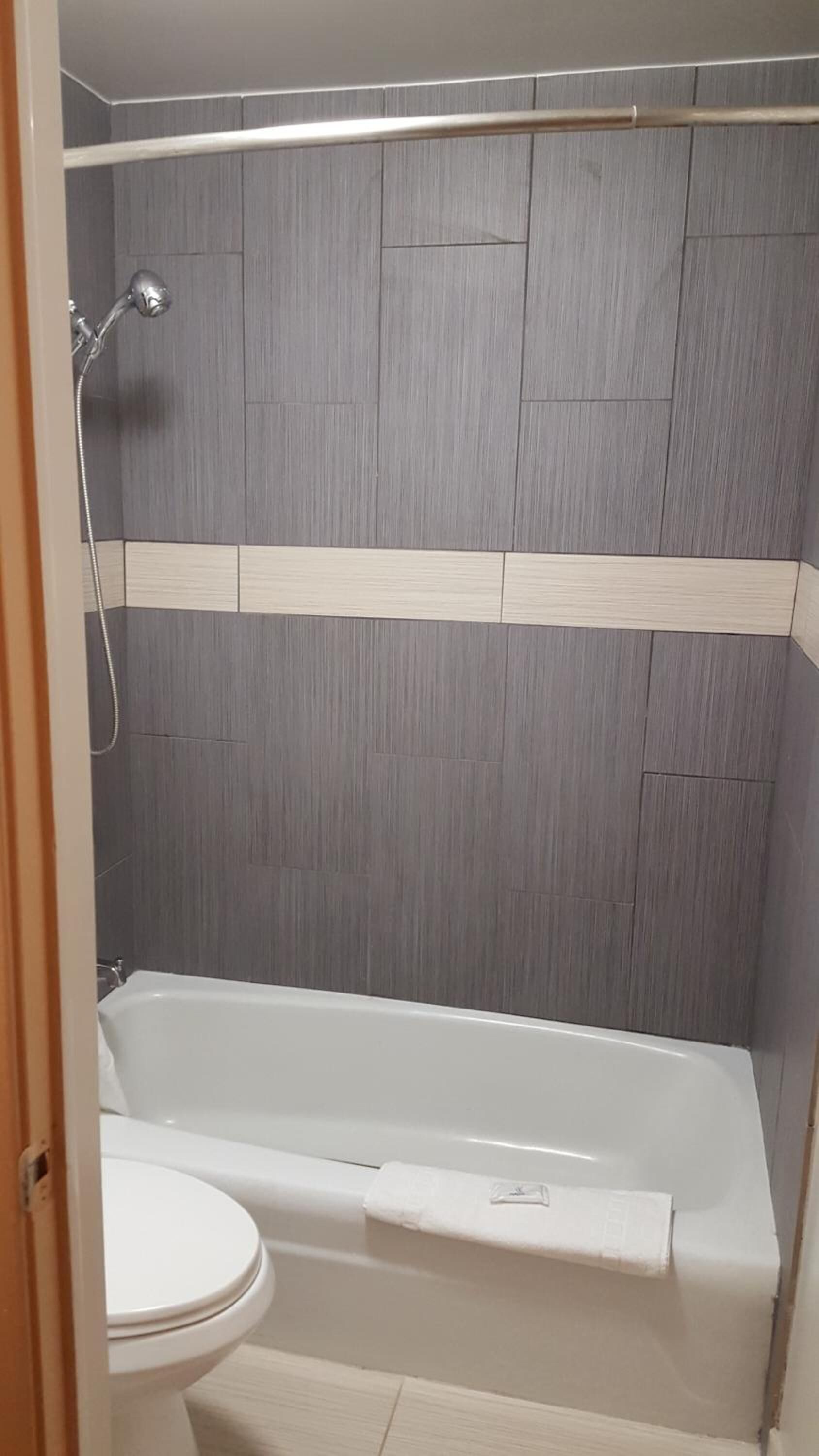 A bathroom with a bathtub, a toilet, and a shower area.