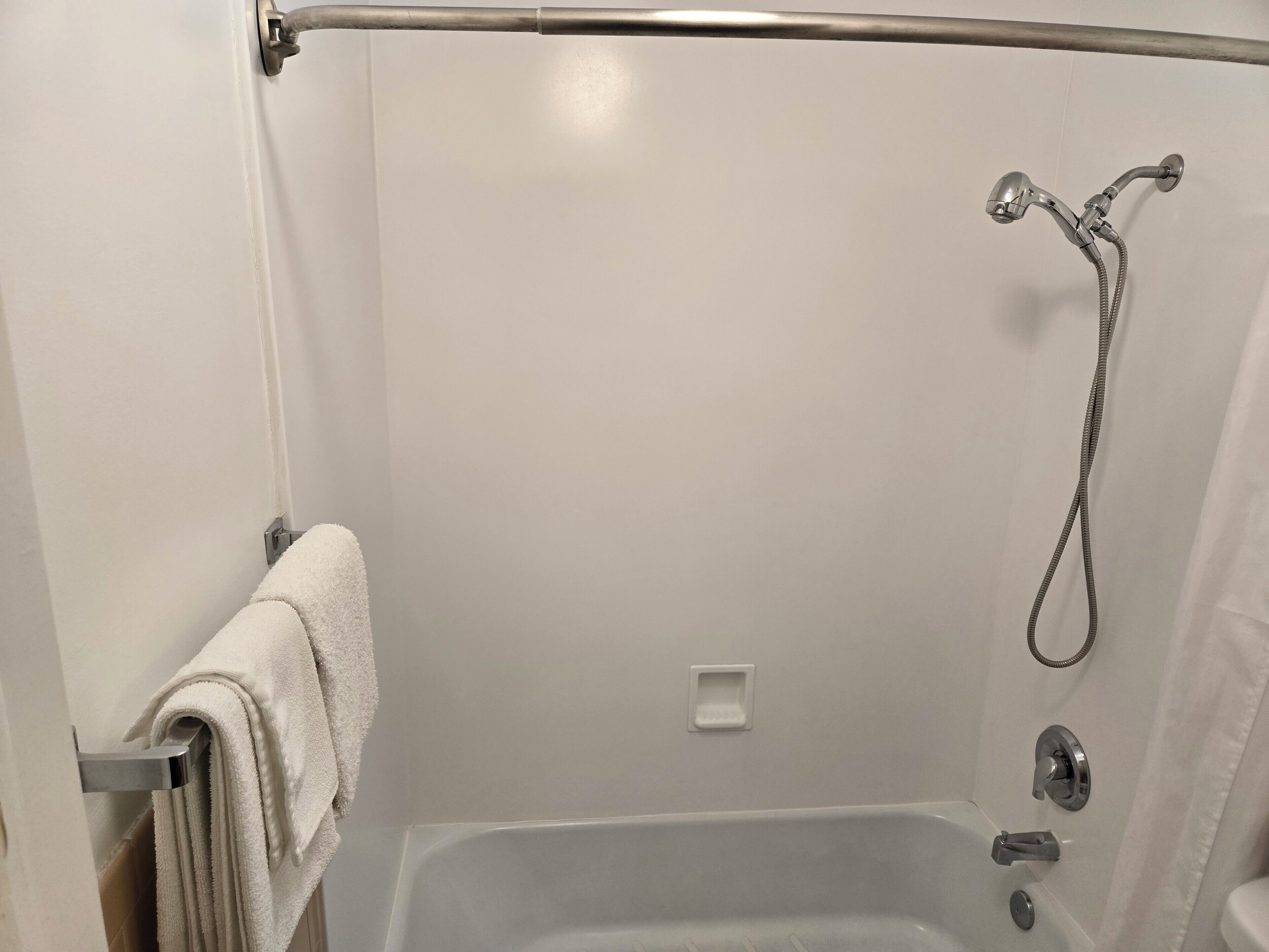 A shower with a handheld showerhead and a towel rack.