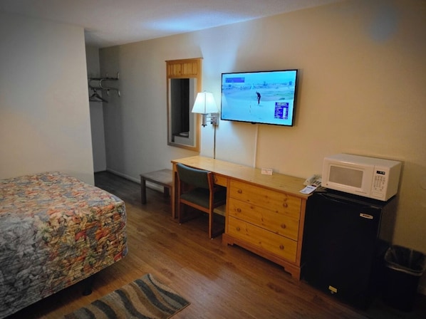 A hotel room with a bed, a desk, a television, a microwave, and a trash bin. - Travelers Lodge Motel Marshall (Marshall)