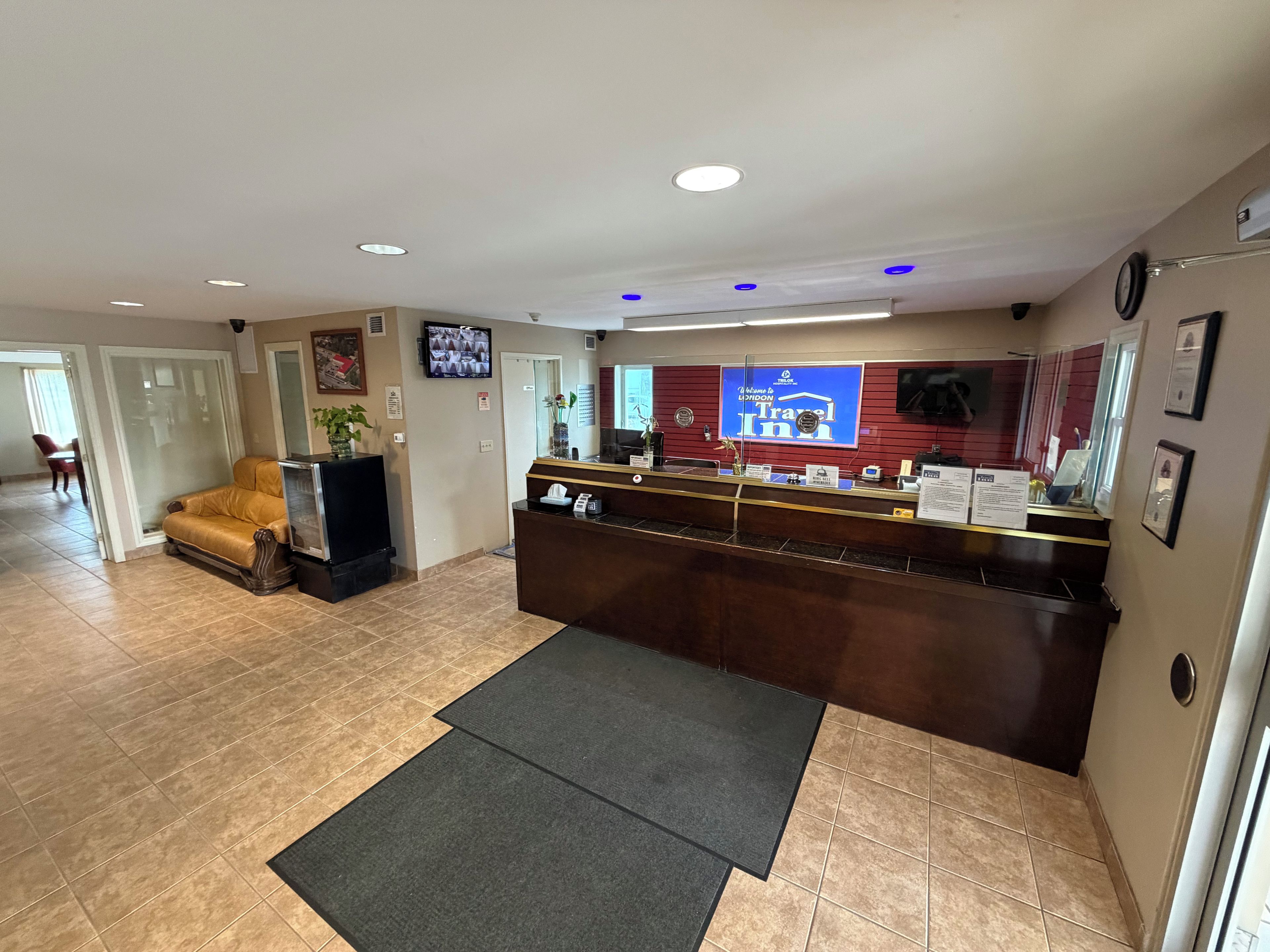 A reception area with a reception desk, a television mounted on the wall, and a sofa in the background.