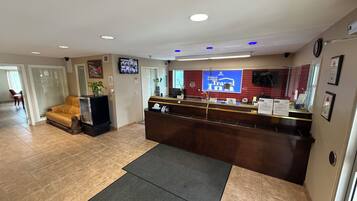 A reception area with a reception desk, a television mounted on the wall, and a sofa in the background.
