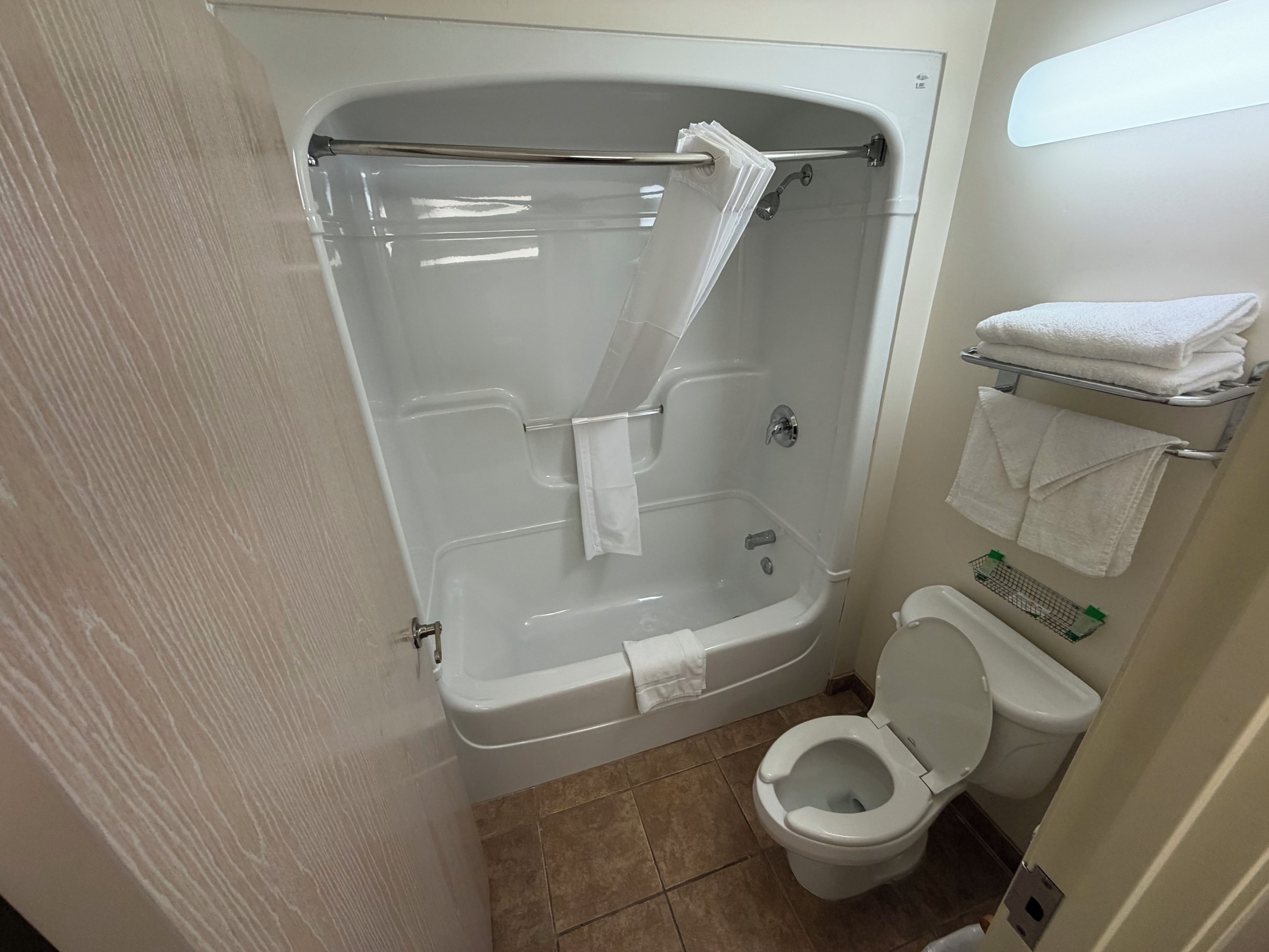 A bathroom with a bathtub, toilet, and a towel rack with folded towels.