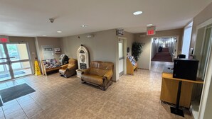 A lobby with a reception desk, two leather armchairs, a plant, and a sign indicating the exit.