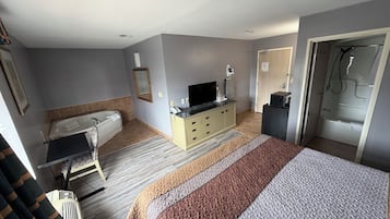 A hotel room with a bed, a television, a bathroom with a bathtub, and a shower.