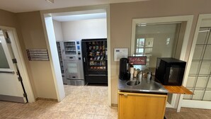 A hotel room with a kitchenette, a vending machine, and a coffee machine.