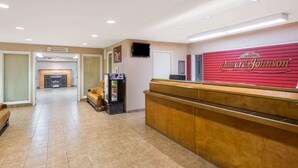 A hotel reception area with a reception desk, a television mounted on the wall, and a sign indicating a meeting room and breakfast room. - London Travel Inn (London)