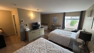 Habitación de hotel con dos camas, un escritorio, un televisor de pantalla plana, un baño pequeño y una ventana con vistas.