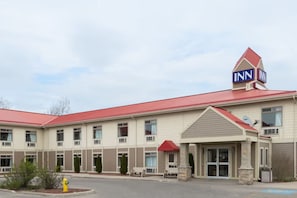A multi-story hotel with a red roof, a prominent 'INN' sign, and a covered entrance. - London Travel Inn (London)