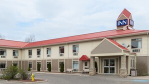A multi-story hotel with a red roof, a prominent 'INN' sign, and a driveway leading to the entrance. - London Travel Inn (London)