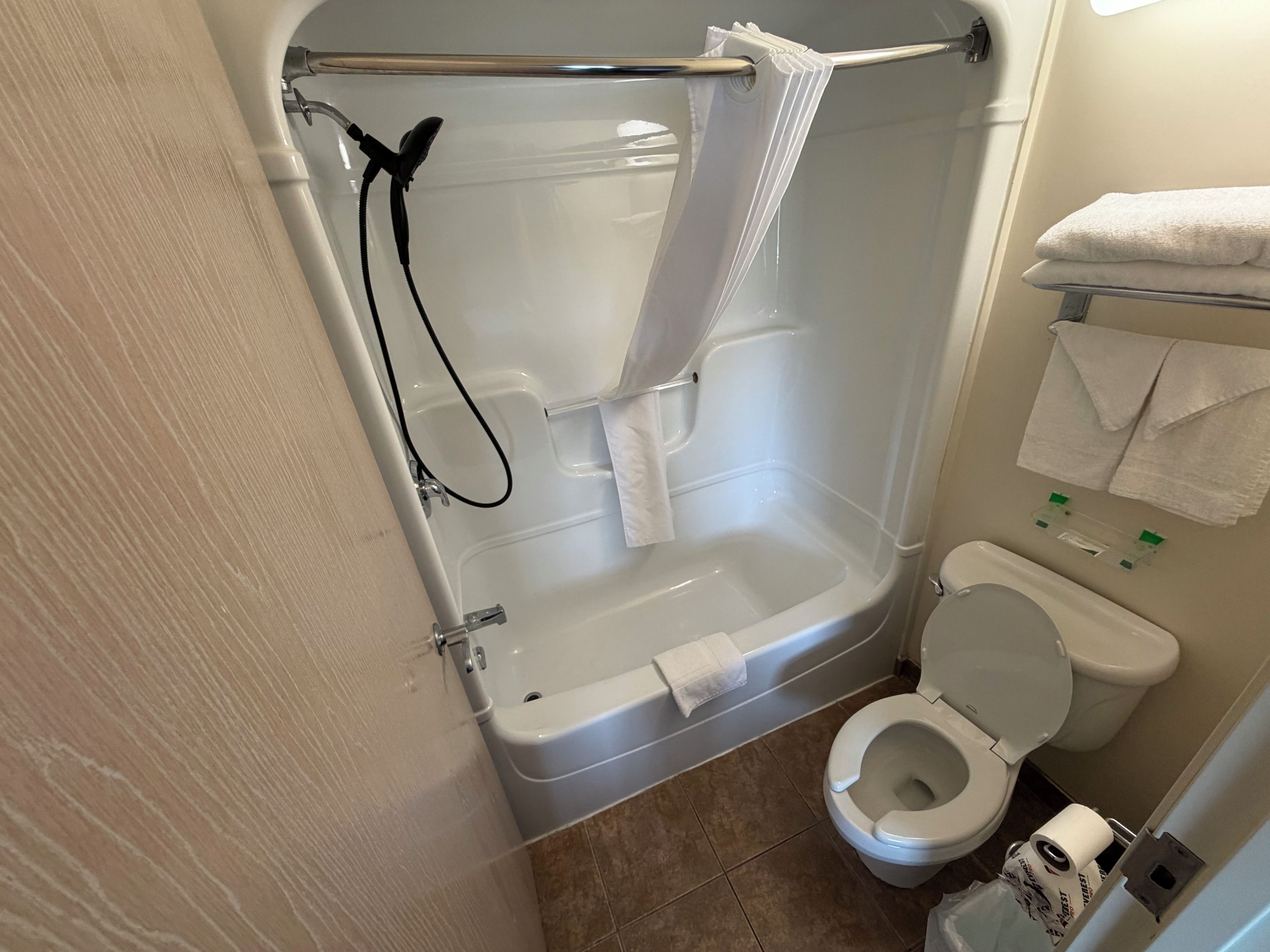 A bathroom with a bathtub, toilet, and shower area.
