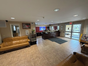 A lobby with a reception desk, a leather sofa, a small refrigerator, and a tiled floor. - London Travel Inn (London)