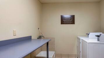 A small laundry area with a sink, a washing machine, and a dryer. There is a sign on the wall with instructions for guests.