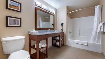 A bathroom with a toilet, sink, mirror, and shower.