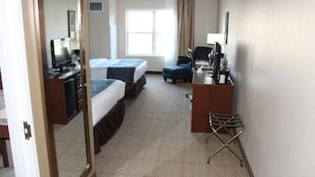 A hotel room with two beds, a desk with a computer, a chair, and a mirror.