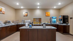 Eine moderne Küchenzeile mit einer zentralen Kochinsel, ausgestattet mit verschiedenen Geräten und einer Kaffeestation.