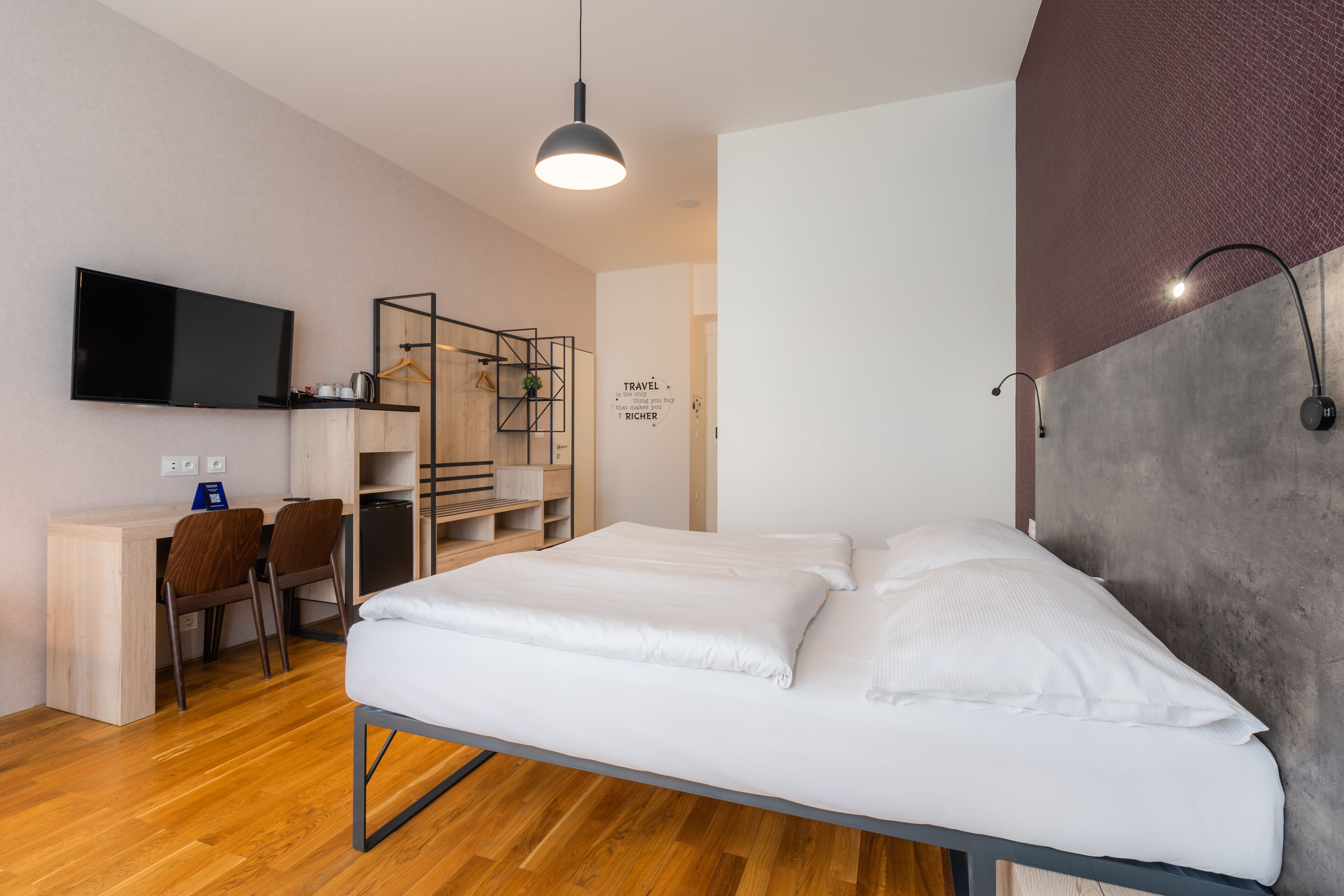 Et moderne hotelværelse med seng, skrivebord, stole og fjernsyn.